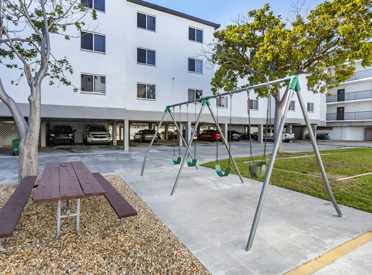 Swing Set in Front Of Picnic Tables Between Building Exteriors