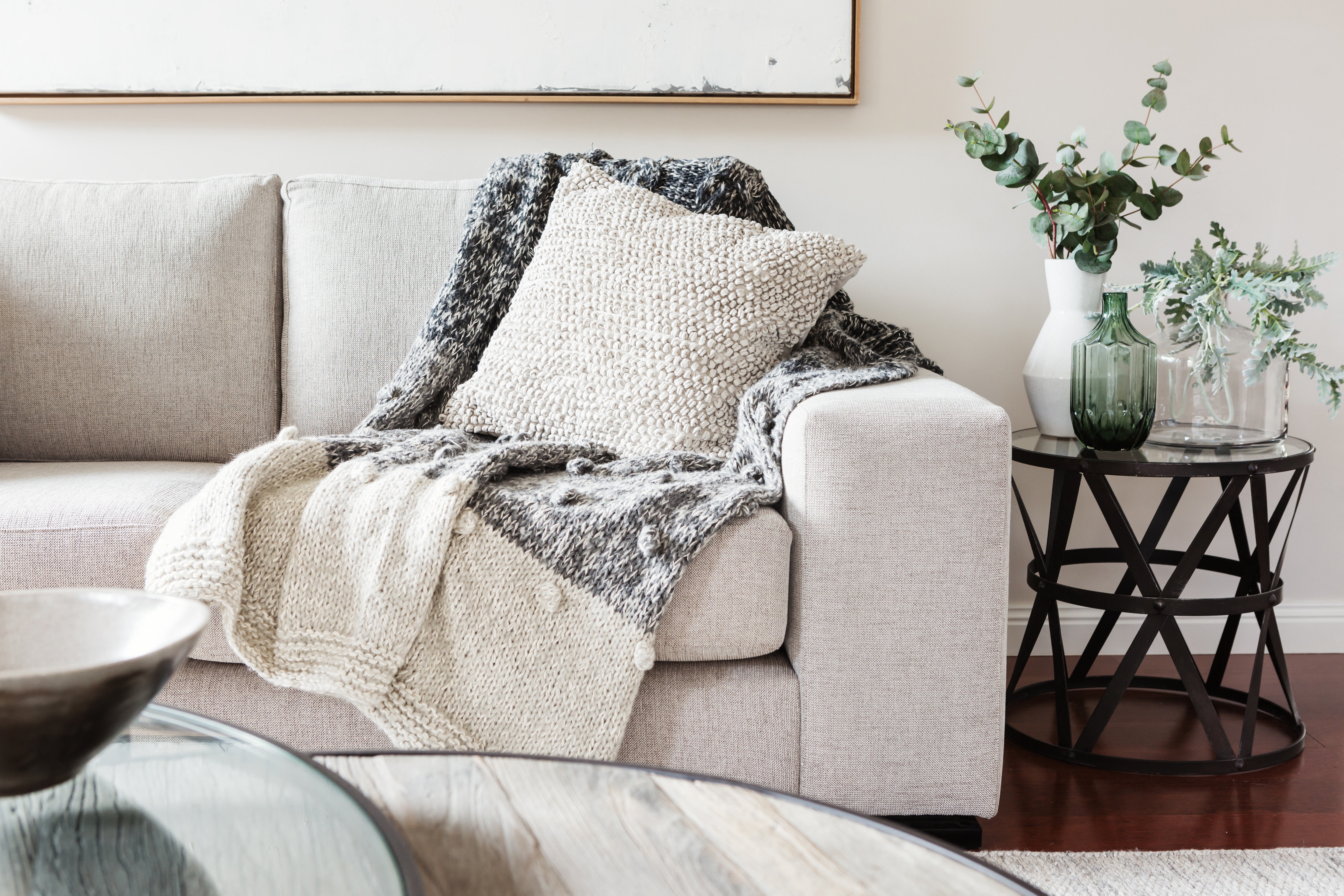 A grey couch with a blanket on it.