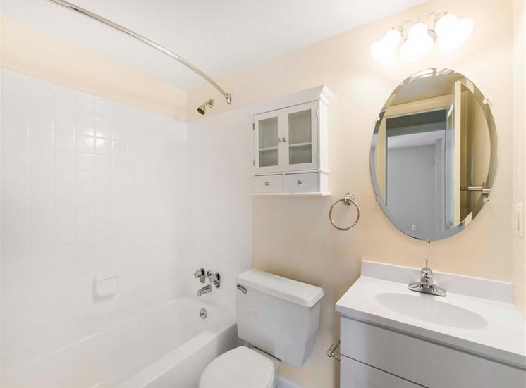 Bathroom with White Cabinets and Counter with Round Mirror