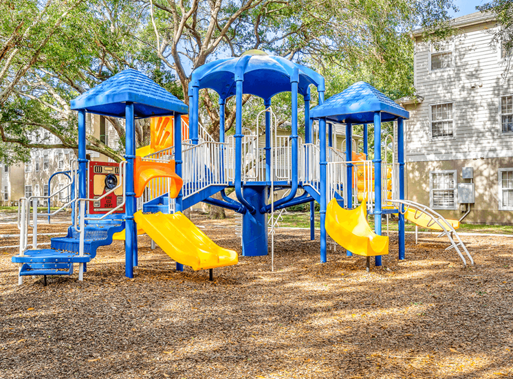 Playground with multiple slides, stairs surrounded by native landscaping and building exterior