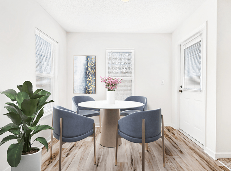 Virtually staged dining room with wood table and grey accent chairs. Hardwood flooring and natural lights with windows and door leading to outside.