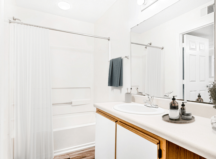 Virtually staged; Bathroom with wood cabinets, white countertops, and chrome finish outs. Bathroom accessories and grey towel
