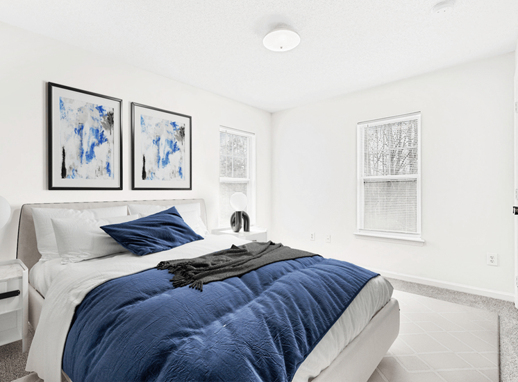 Virtually staged; Carpeted bedroom with two windows, bed and night stands with blue/ grey accents and wall art