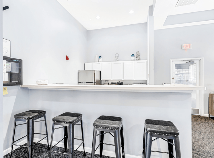 Clubroom kitchen. Bar area with four bar stools and a hightop counter.