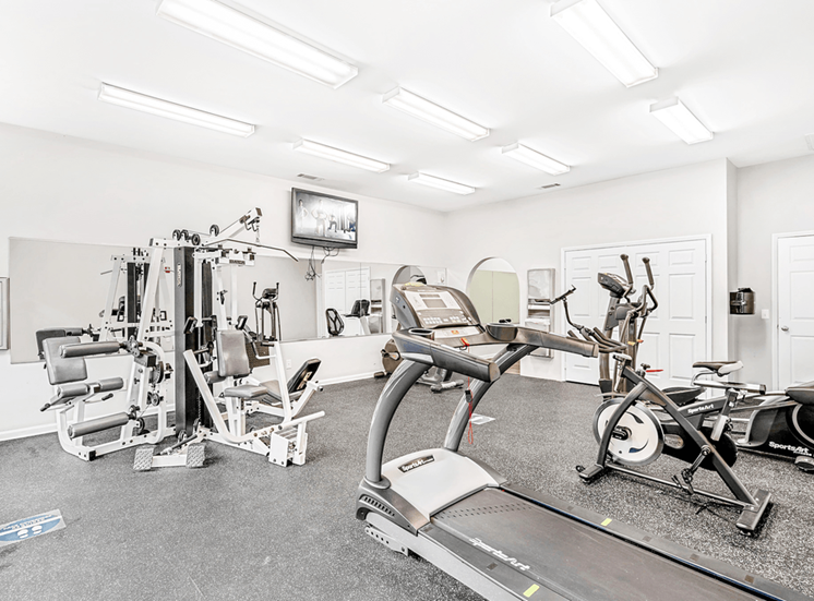 Bright Fitness Center with Exercise Equipment and Mirrored Wall and Mounted TV