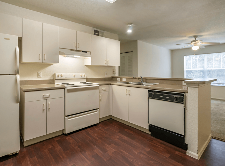 Kitchen with hardwood style flooring, white appliances, white cabinetry, and breakfast bar