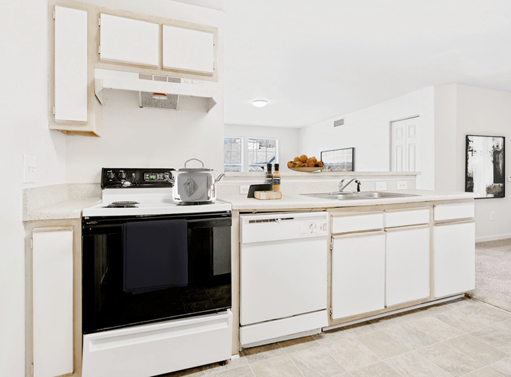 Virtually staged kitchen with tile floors, white appliances, and wood cabinets.