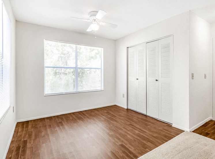 A study with hardwood-style floors, a ceiling fan, windows, and a closet, near the entryway into the apartment.