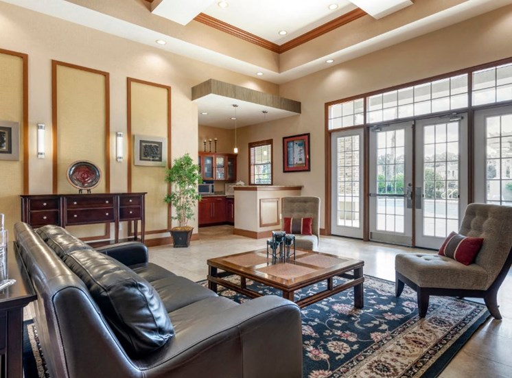 Clubhouse lounge with couch, chair, coffee table, high ceilings, and large windows for natural lighting