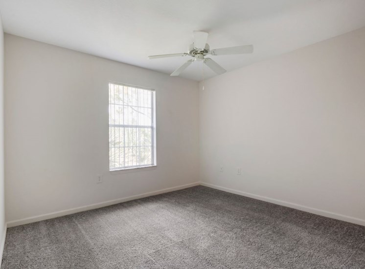 Spacious bedroom with carpet flooring, multi speed ceiling fan, and large window for natural lighting