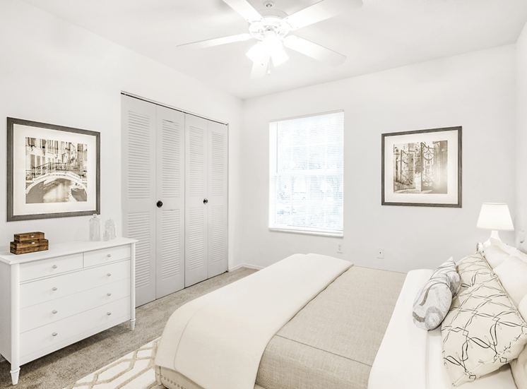 Virtually staged bedroom with carpet, accent rug, ceiling fan with light, white dresser, closet, and large window