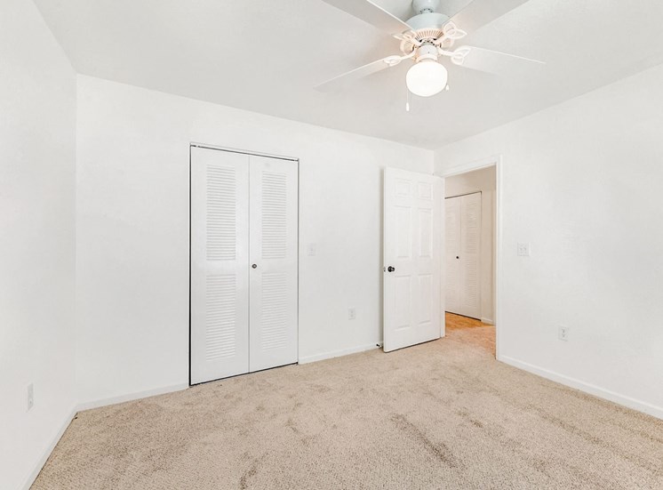 Vacant bedroom with carpet, a ceiling fan, and a closet.