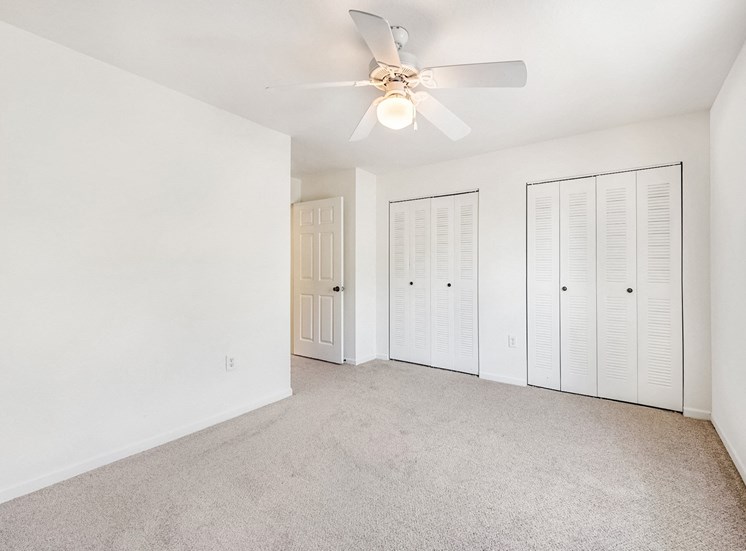 Vacant bedroom with a window, ceiling fan, and carpet.