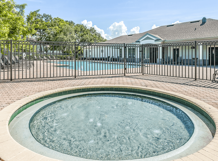 Gated wading pool with swimming pool and deck in background and surrounding native landscape