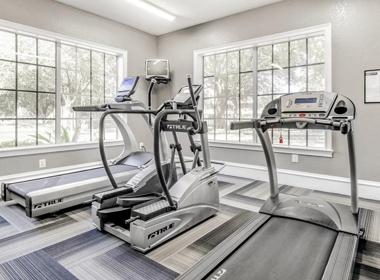 Fitness center with cardio machines, large windows and television