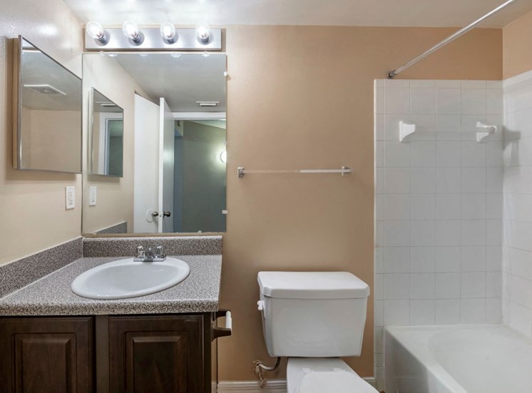 Bathroom with large mirror, vanity lighting, and tiled shower