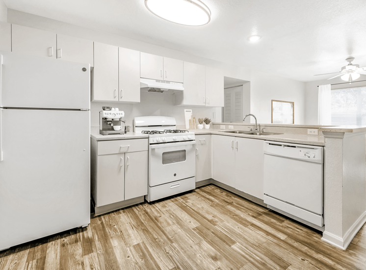 Kitchen with hardwood style flooring, white appliances, white cabinets, and breakfast bar
