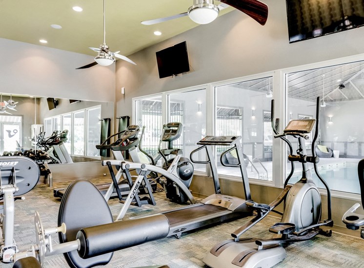Fitness center equipped with strength training equipment, cardio equipment, and yoga equipment overlooking the indoor pool.