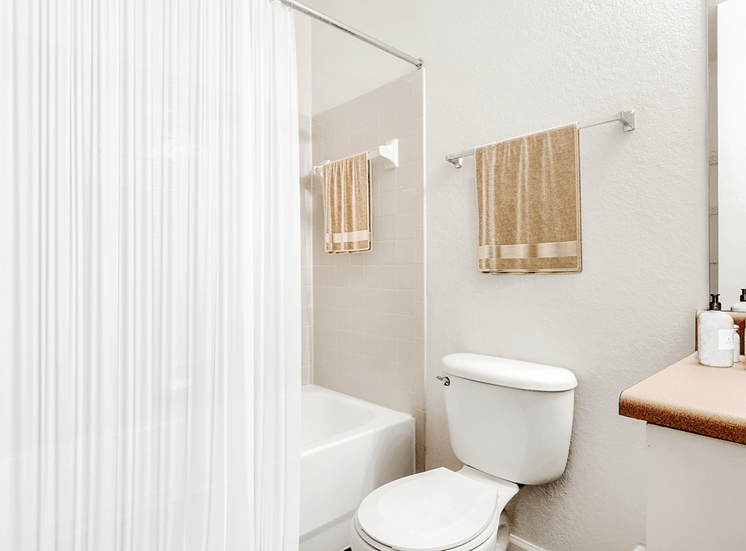Virtually staged bathroom with a tiled tub, shower curtain, toilet