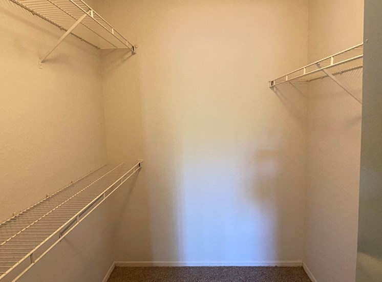 Spacious carpeted closet with mounted metal shelves