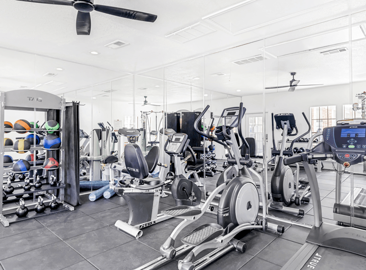 Fitness center with cardio machines, kettlebells and exercise balls, wall mirrors, ceiling fan and recessed lighting