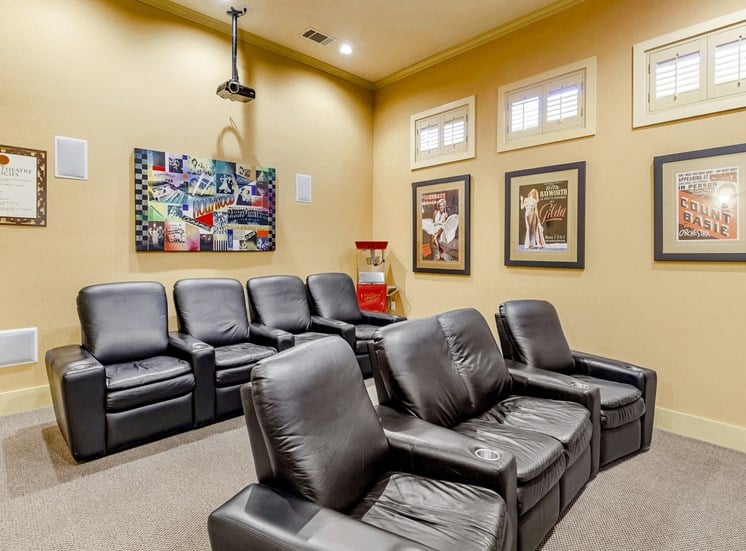 Movie theater with black leather recliners and decorative photos in the background.