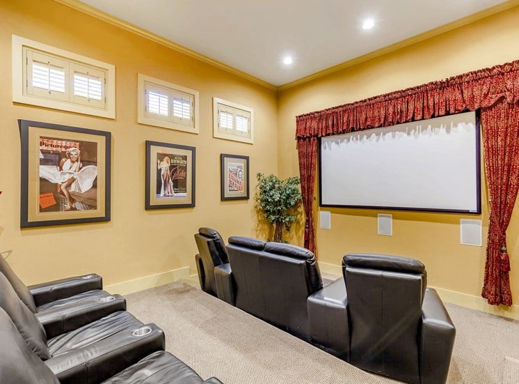 Theater room with black leather recliners and screen projector mounted on a yellow wall