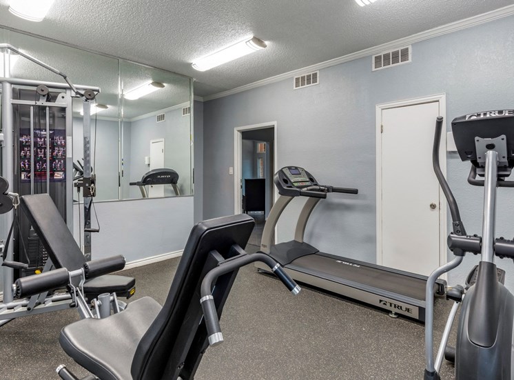 Fitness center complete with cardio and weight training equipment, gray walls, and large mirrors.