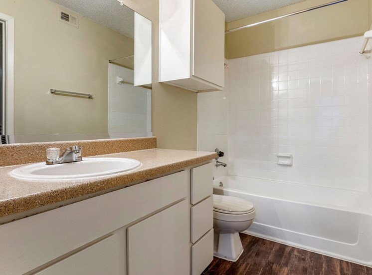 Bathroom space with large vanity, two-tone paint, wood-style flooring, storage above the toilet, and white surfaced subway tile and bath tub.