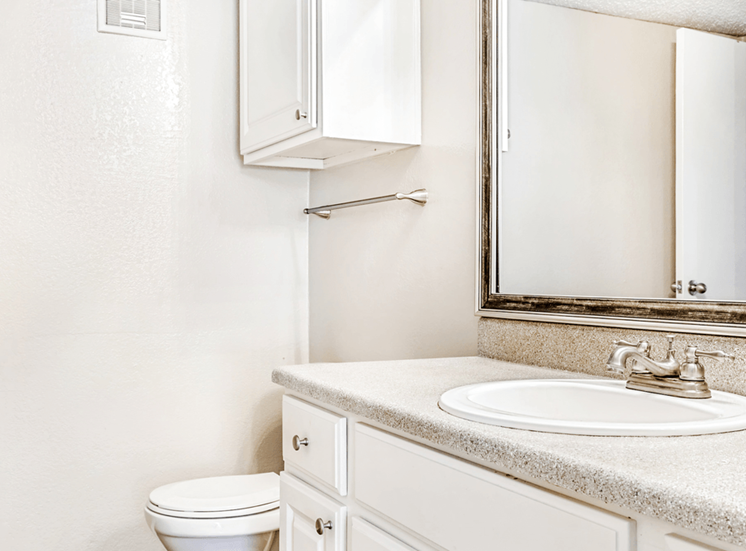 Bathroom with white cabinetry, granite inspired countertops, custom mirror vanity