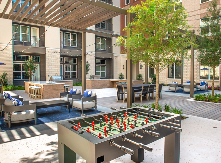 Courtyard outdoor gaming area with foosball table, alfresco seating with gas grill area and pergolas