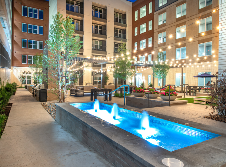 Fountain water feature near courtyard lounge and outdoor gaming area with native landscape