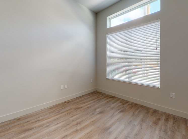 Bedroom with wood style flooring and large window with blinds