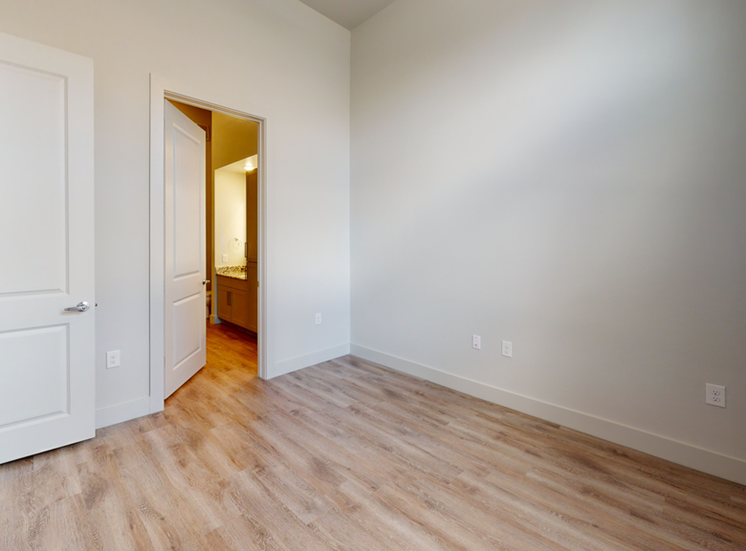 Bedroom with wood style flooring and en-suite bathroom entry