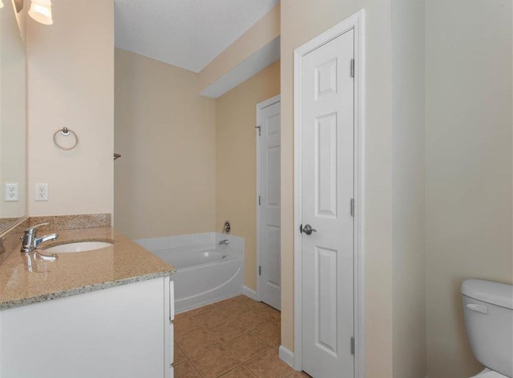 Bathroom with Bathtub Tan Counters White Cabinets and Linen Closet Door