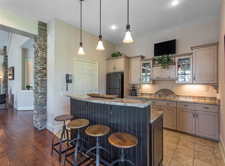 Clubhouse Kitchen with Tan Counters Black Appliances and Wood and Metal Stools at Breakfast Bar
