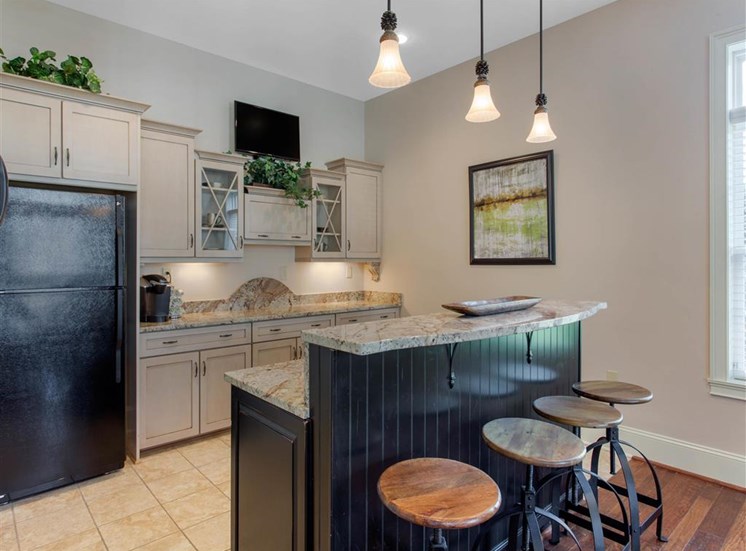 Clubhouse Kitchen with Tan Counters Black Appliances and Wood and Metal Stools at Breakfast Bar