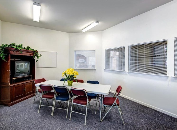 Resident Lounge Room with Large Windows Folding Table and Chairs in Front of a TV in an Entertainment Center