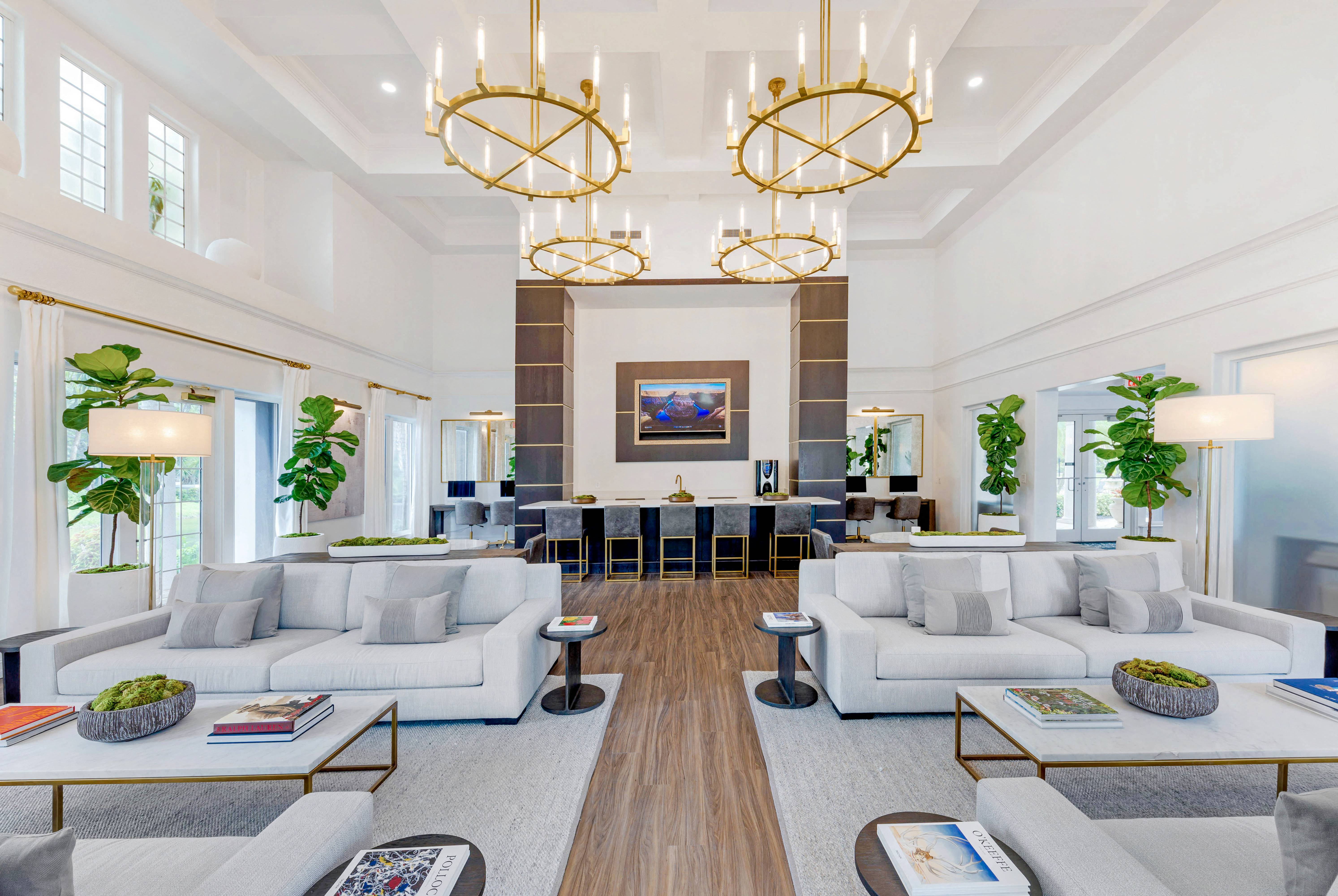 Clubhouse Seating Area with Contemporary Decorations Coffee Tables, Couches and Decorative Trees and Gold Chandeliers