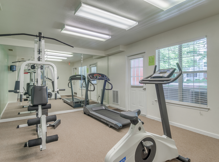 The fitness center is equipped with a weightlifting machine, one treadmill and one stationary bicycle. It is fully carpeted with one picture window on the same wall as the entry door and one wall make of mirrors.