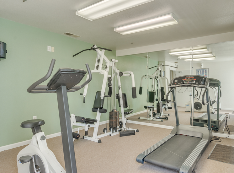 The fitness center is carpeted throughout with one picture window on the same wall as the entry door. The fitness center is equipped with a treadmill, a stationary bicycle, an elliptical and a weightlifting machine.
