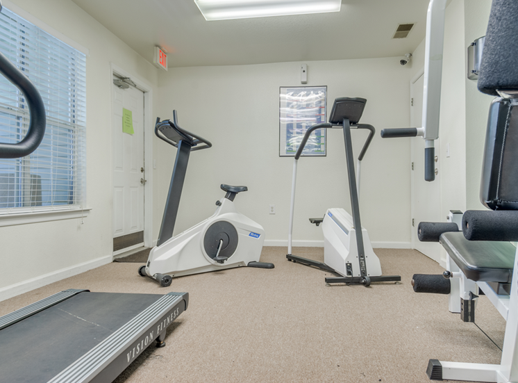 The fitness center is carpeted throughout and one wall is made of mirrors. It is equipped with a weightlifting machine, a treadmill and a stationary bicycle.