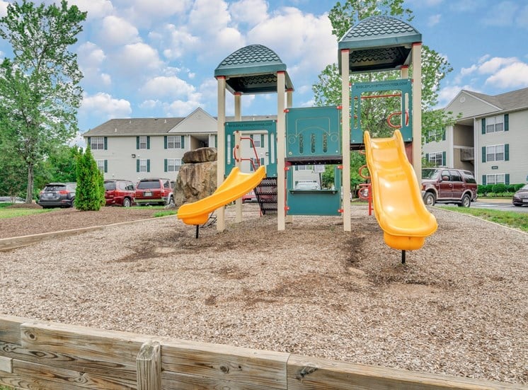 Playground with wood chips in court yard between buildings.