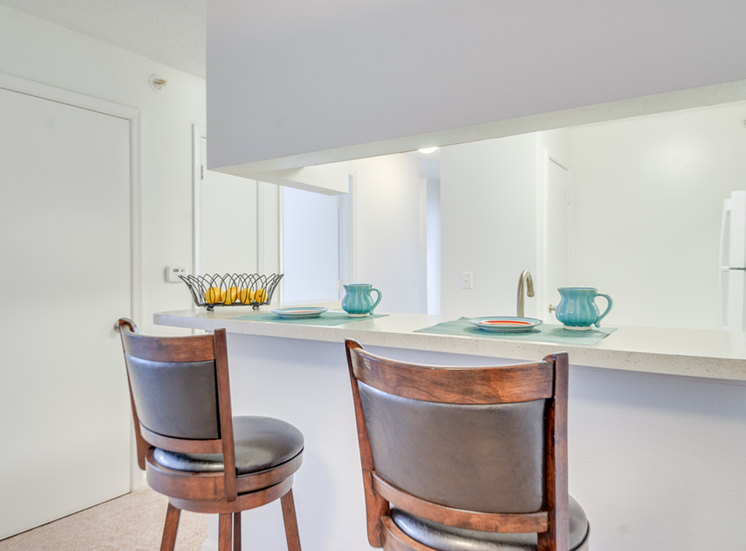 The breakfast bar opens to the kitchen. There are two barstools and place settings for two.