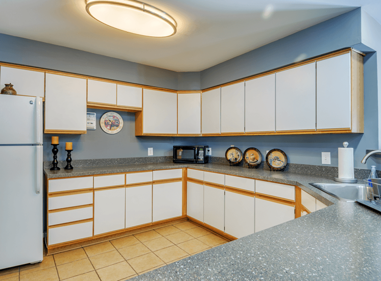 Clubhouse kitchen with tile flooring, white cabinets, and breakfast bar