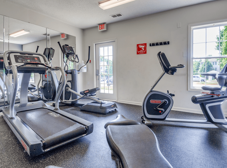 Fitness center with cardio equipment and large windows for natural lighting
