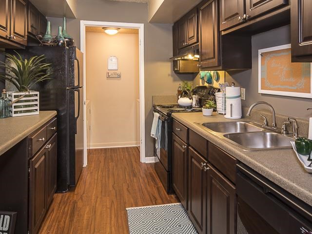 Model Kitchen with Brown Cabinets Black Appliances Grey Counters with Decorations