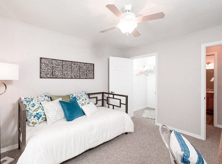 Furnished model apartment featuring a day bed and ceiling fan.
