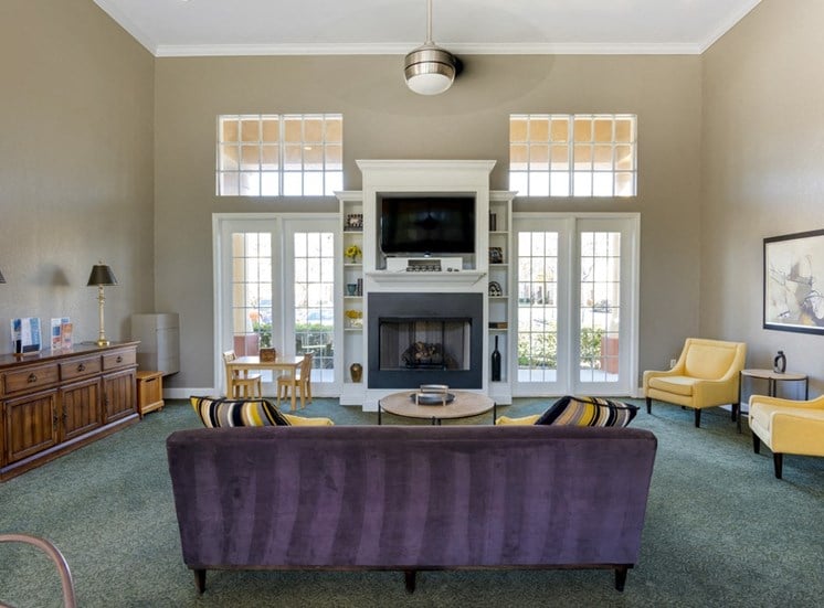 Clubhouse Seating Area Around Fireplace with TV Mounted Above it, Armchairs, Miniature Table, and Buffett Cabinet