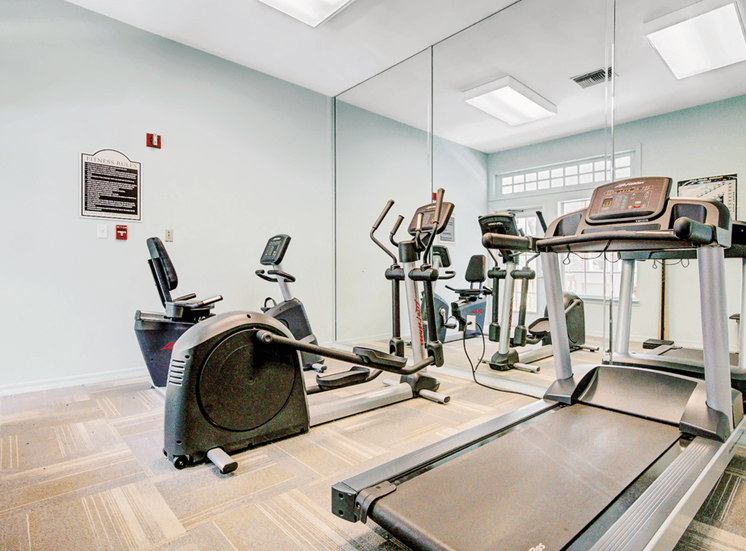 Fitness center with cardio machines and large mirror wall